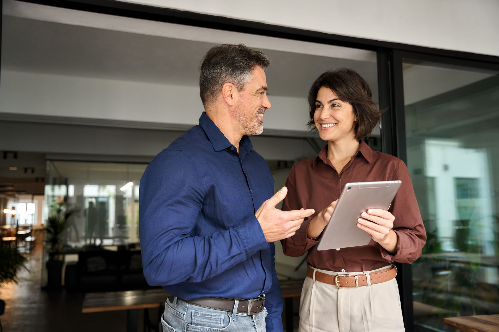 Two happy business colleagues having conversation at office meeting using tab. Two happy business colleagues having conversation at office meeting using tab.
