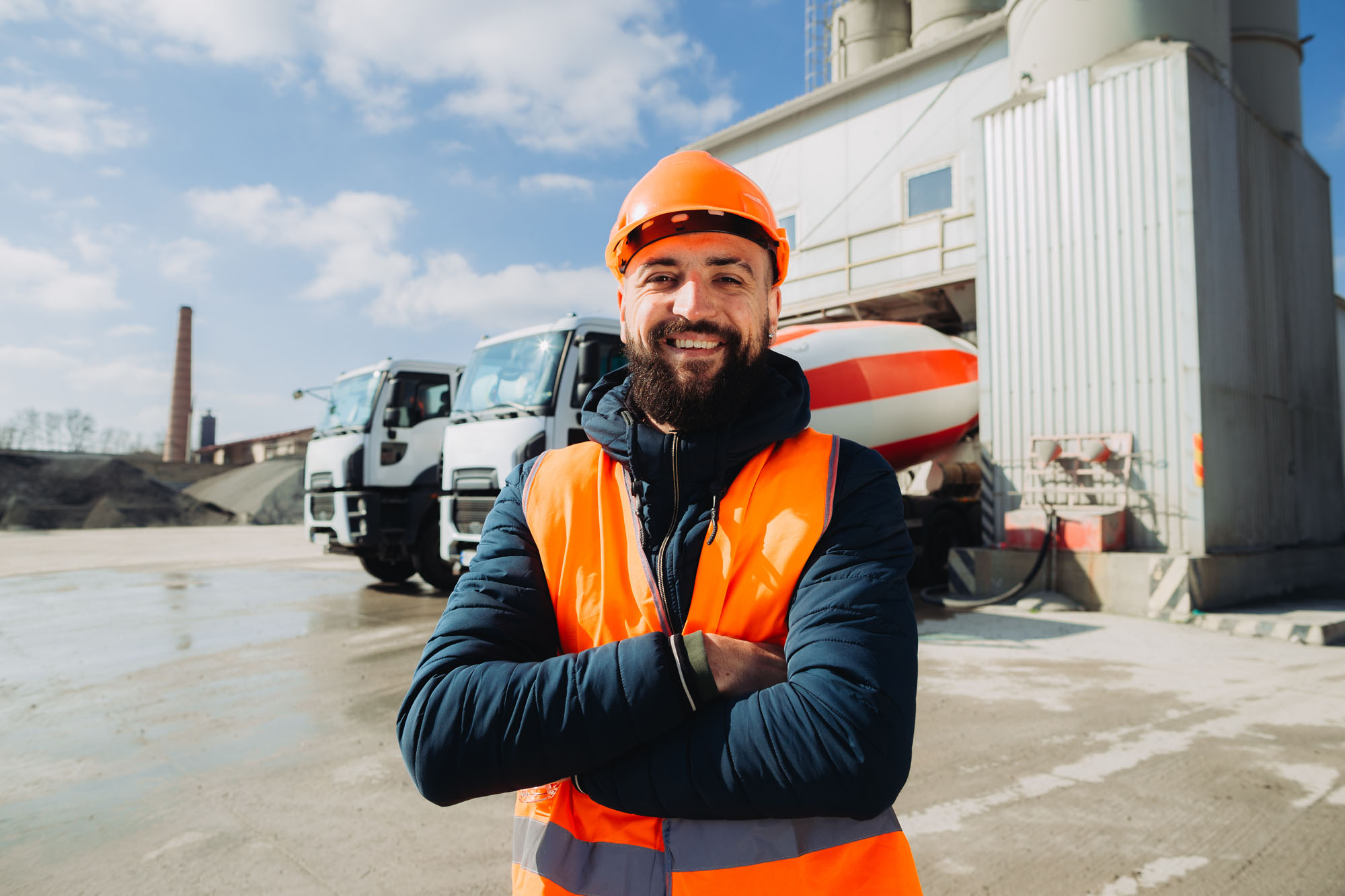 Construction worker smiling with crossed arms at concrete production plant Construction worker smiling with crossed arms at concrete production plant